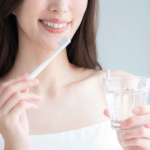 歯ブラシとコップを持つ女性